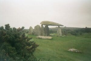 Pentre Ifan, standing stones on a green lawn on what looks to be a foggy day.