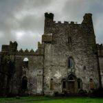 Leap Castle stands above a verdant lawn on an ominous, overcast day.