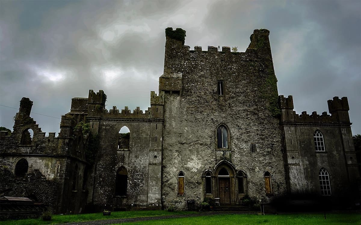 Leap Castle stands above a verdant lawn on an ominous, overcast day.